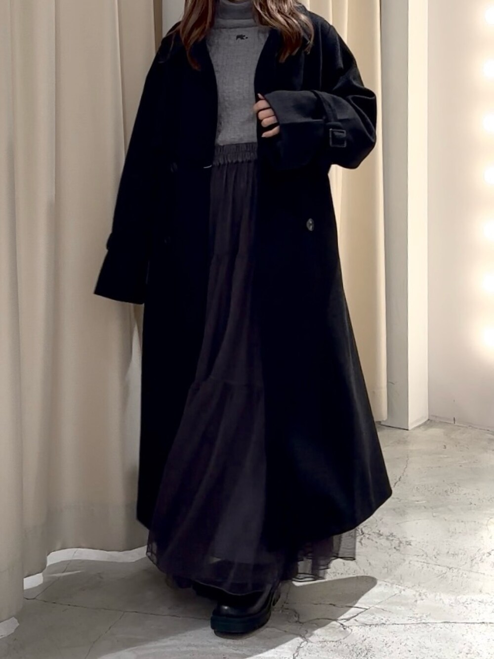 グレー系のニット/セーター、ブラック系のステンカラーコートを着用したレディースの冬コーディネートの7枚目の写真