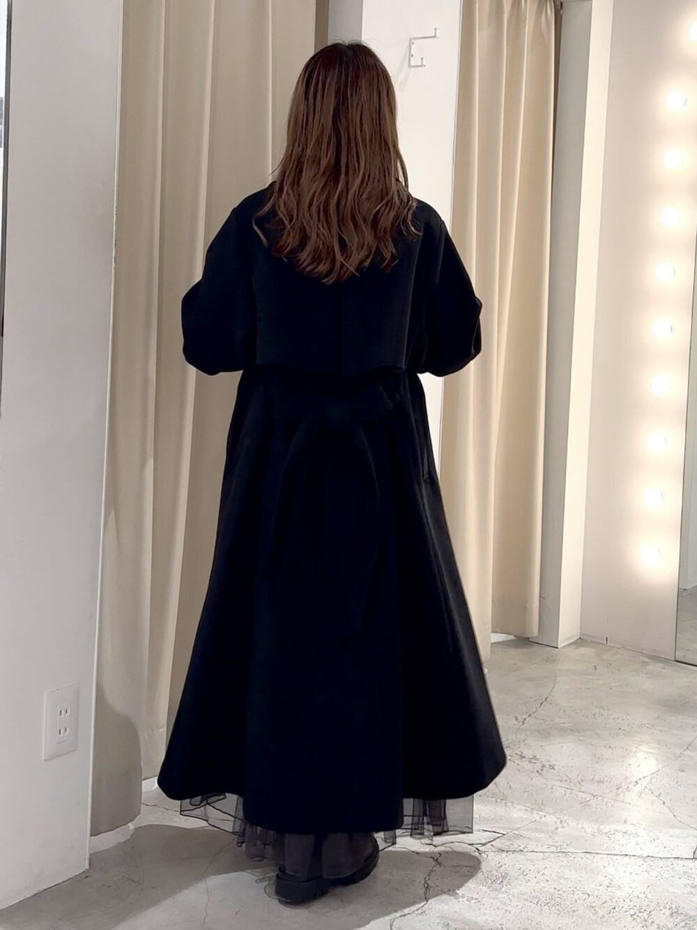 グレー系のニット/セーター、ブラック系のステンカラーコートを着用したレディースの冬コーディネートの8枚目の写真