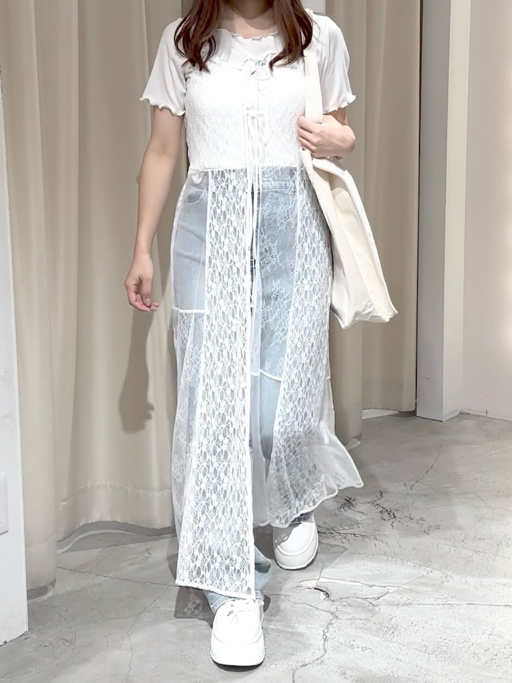 ホワイト系のワンピース、ブルー系のデニムパンツ、ホワイト系のトートバッグを着用したレディースの夏コーディネートの2枚目の写真