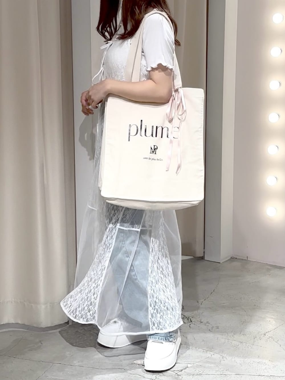 ホワイト系のワンピース、ブルー系のデニムパンツ、ホワイト系のトートバッグを着用したレディースの夏コーディネートの4枚目の写真