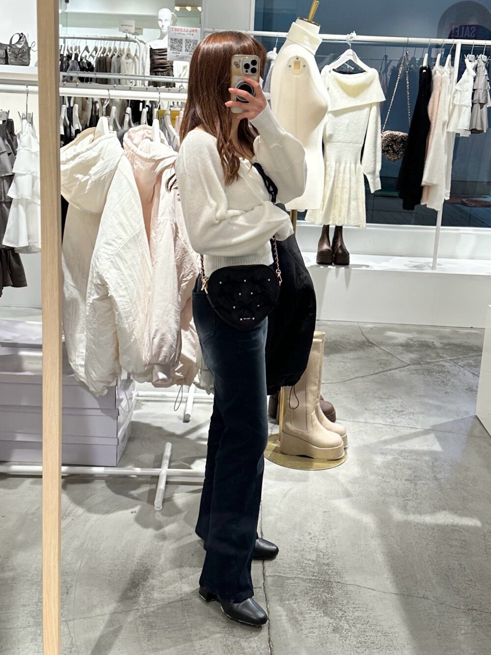 ブルー系のデニムパンツ、ホワイト系のニット/セーター、ブラック系のショルダーバッグを着用したレディースの冬コーディネートの3枚目の写真