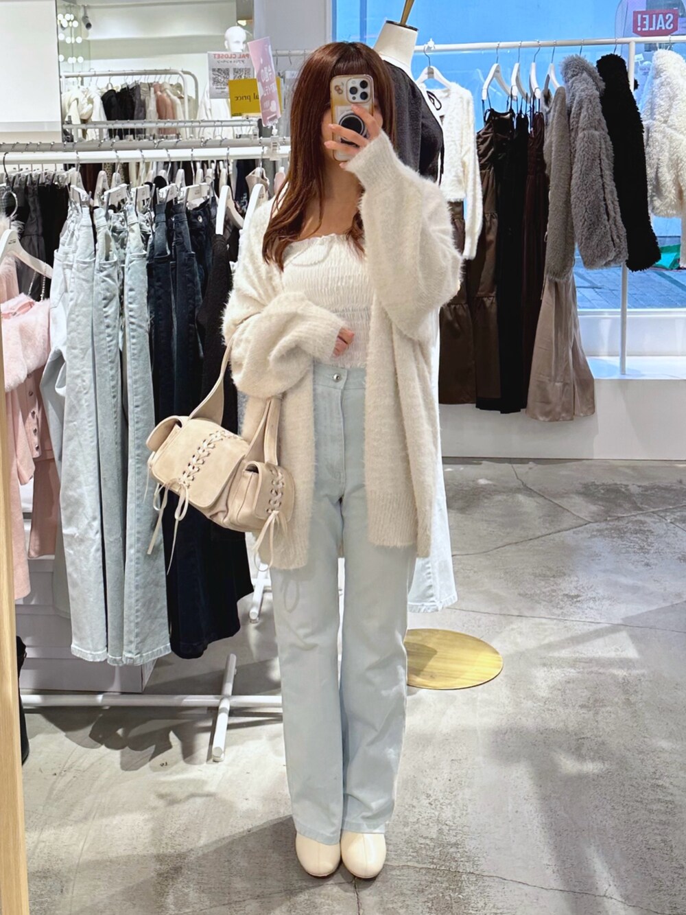 ホワイト系のショルダーバッグ、ホワイト系のカーディガン/ボレロ、ブルー系のデニムパンツを着用したレディースの冬コーディネートの2枚目の写真