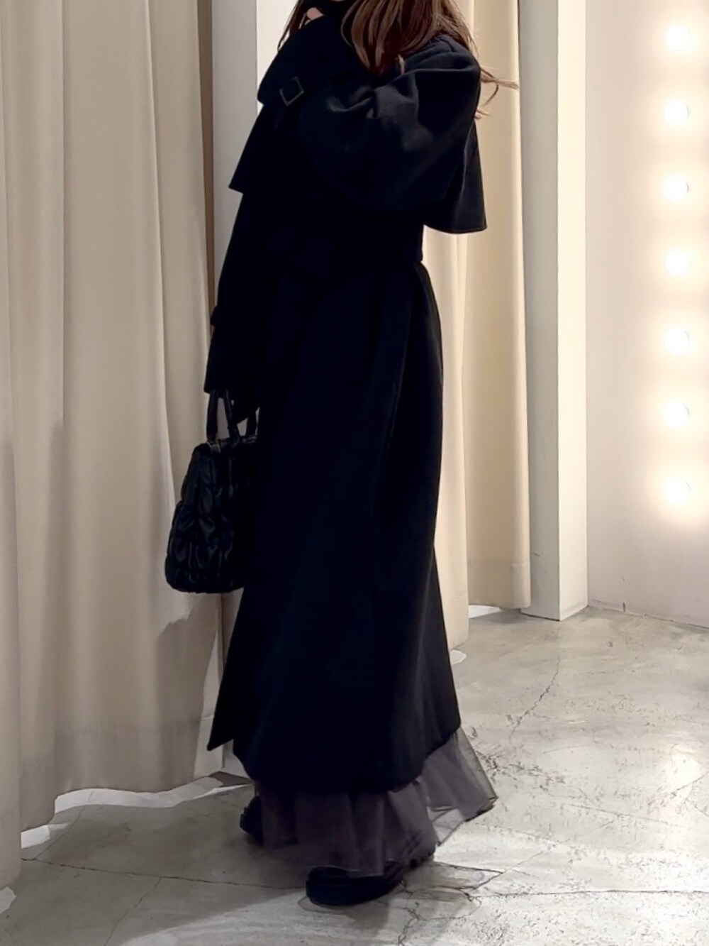 グレー系のニット/セーター、ブラック系のステンカラーコートを着用したレディースの冬コーディネートの5枚目の写真