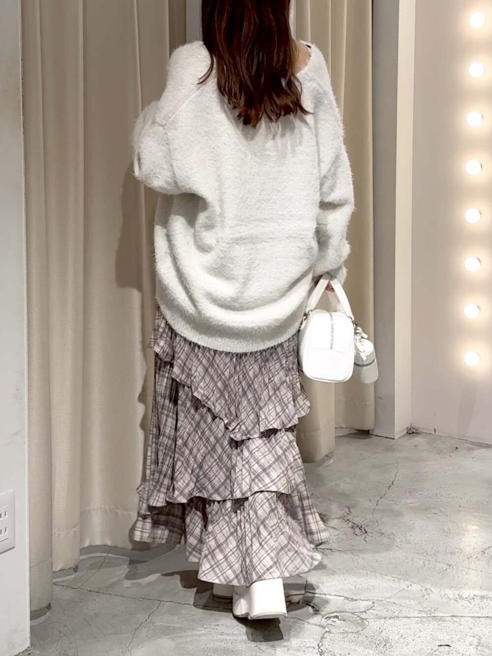 ホワイト系のハンドバッグ、ホワイト系のカーディガン/ボレロ、ブラウン系のスカートを着用したレディースの冬コーディネートの9枚目の写真