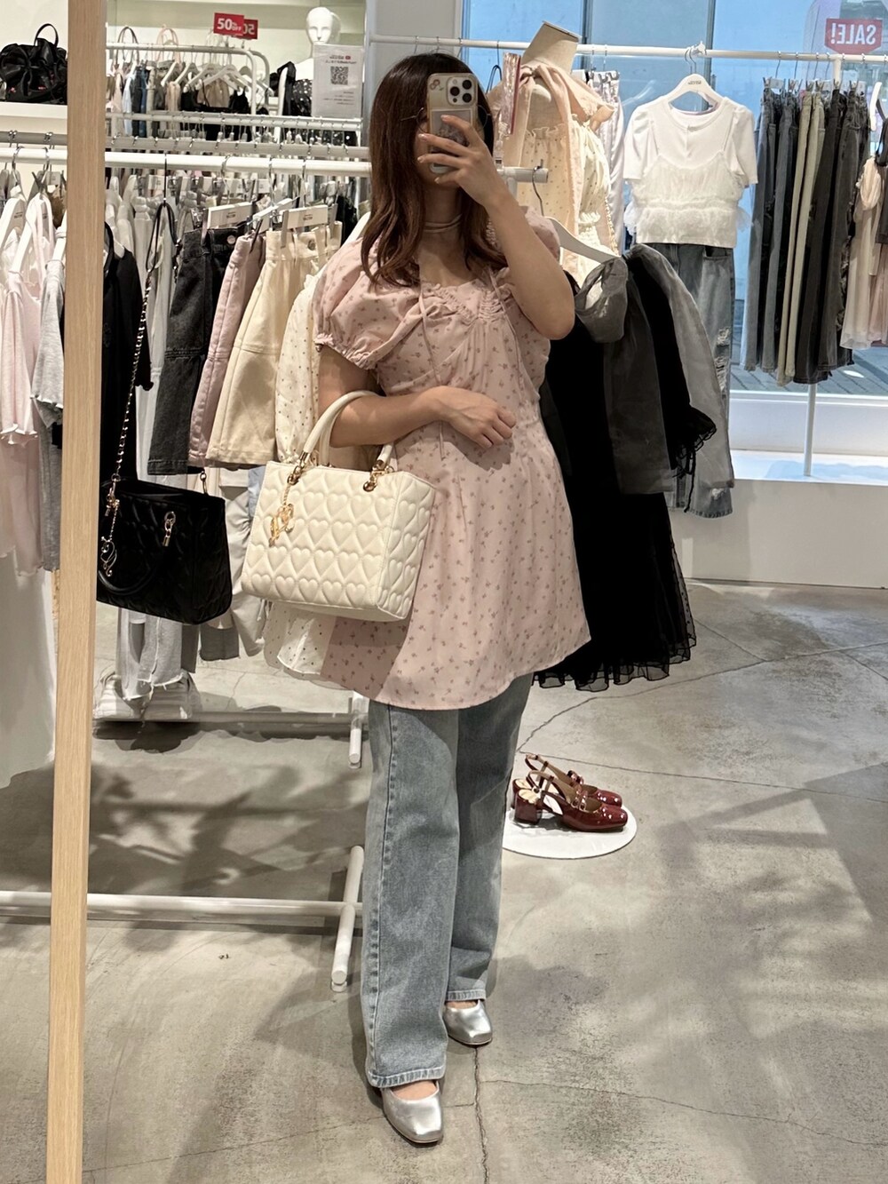 ピンク系のワンピース、ブルー系のデニムパンツ、シルバー系のパンプスを着用したレディースの夏コーディネートの6枚目の写真