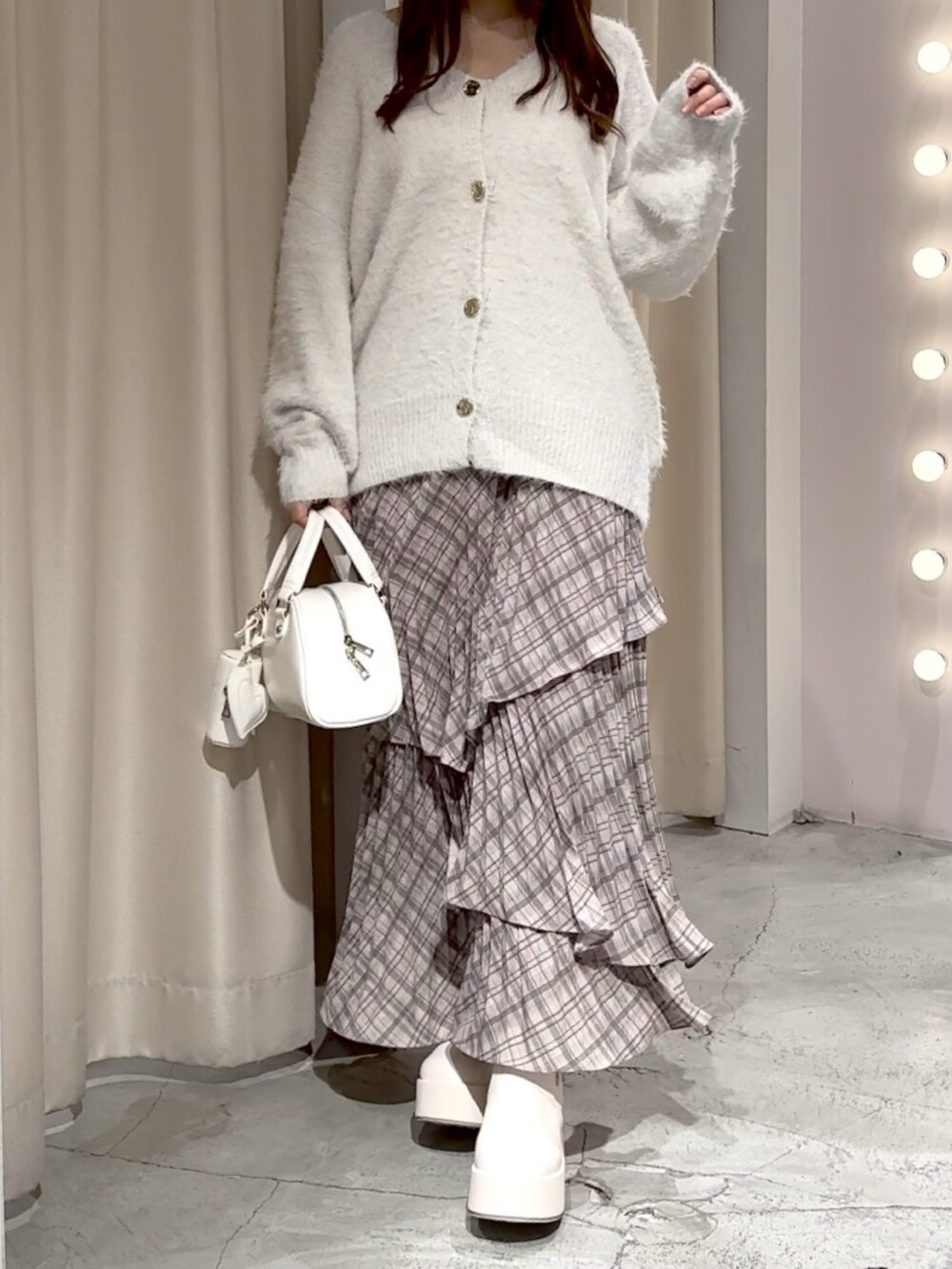 ホワイト系のハンドバッグ、ホワイト系のカーディガン/ボレロ、ブラウン系のスカートを着用したレディースの冬コーディネートの7枚目の写真