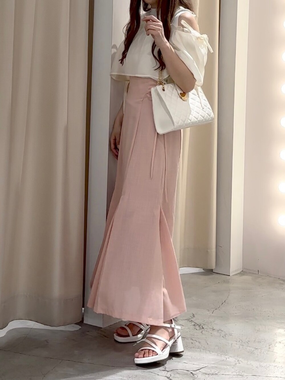 ホワイト系のニット/セーター、ピンク系のスカート、ホワイト系のサンダルを着用したレディースの夏コーディネートの2枚目の写真