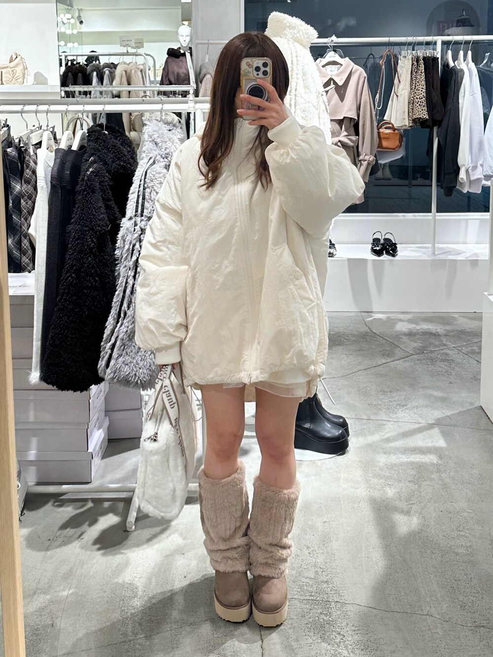 ブラウン系のブーツ、ホワイト系のブルゾンを着用したレディースの冬コーディネートの2枚目の写真