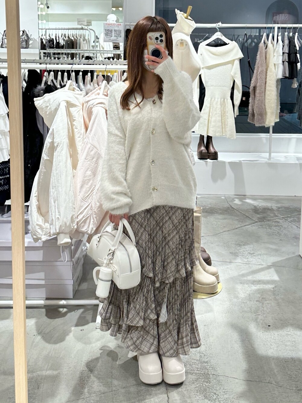 ホワイト系のハンドバッグ、ホワイト系のカーディガン/ボレロ、ブラウン系のスカートを着用したレディースの冬コーディネートの3枚目の写真