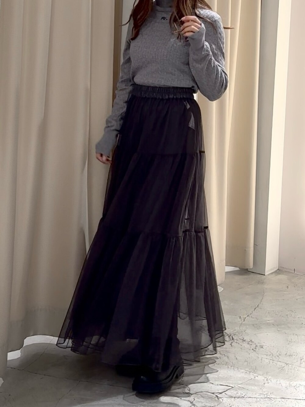 グレー系のニット/セーター、ブラック系のステンカラーコートを着用したレディースの冬コーディネートの9枚目の写真