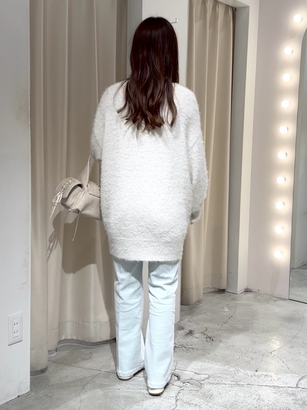 ホワイト系のショルダーバッグ、ホワイト系のカーディガン/ボレロ、ブルー系のデニムパンツを着用したレディースの冬コーディネートの7枚目の写真