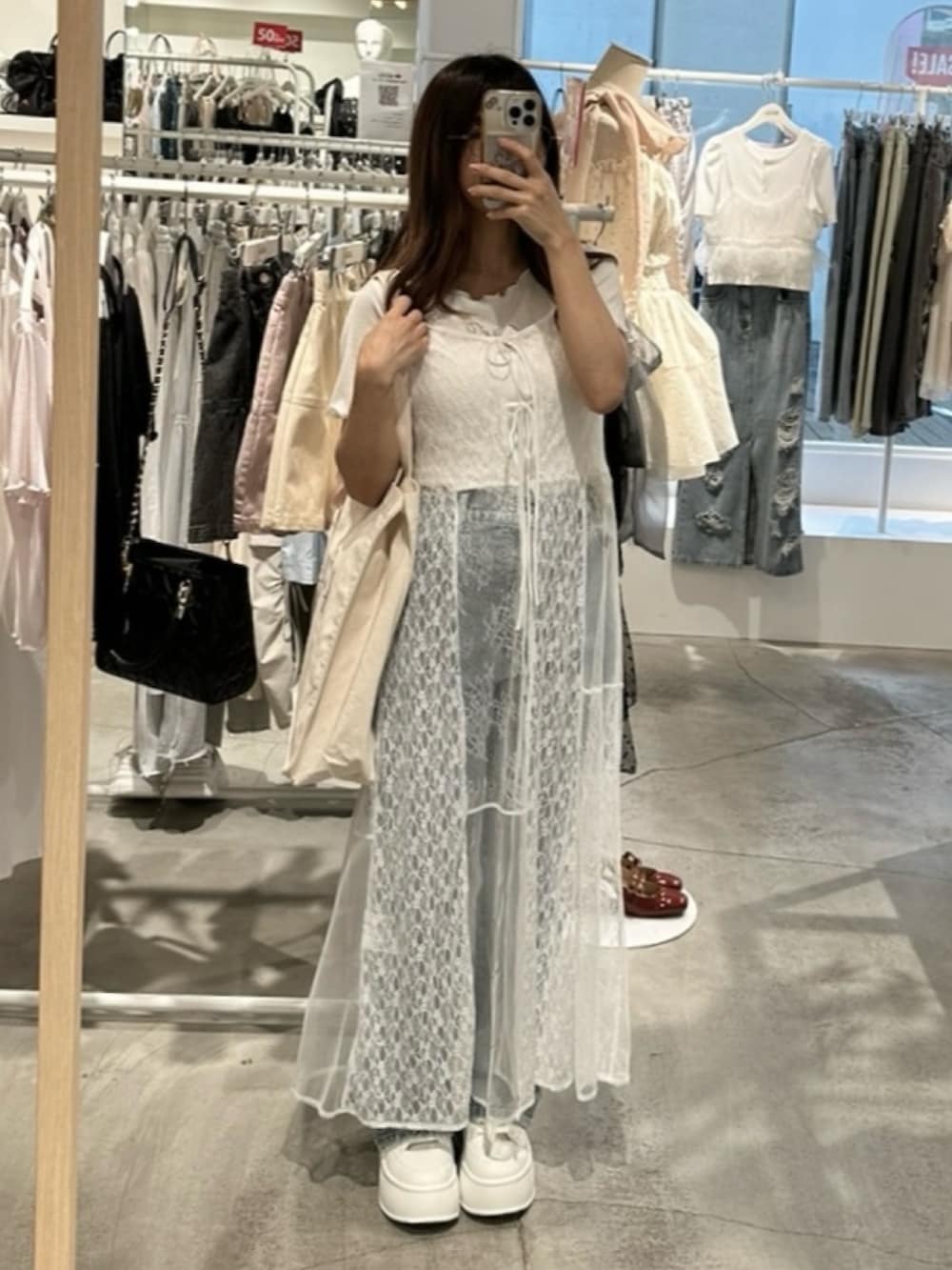 ホワイト系のワンピース、ブルー系のデニムパンツ、ホワイト系のトートバッグを着用したレディースの夏コーディネートの9枚目の写真