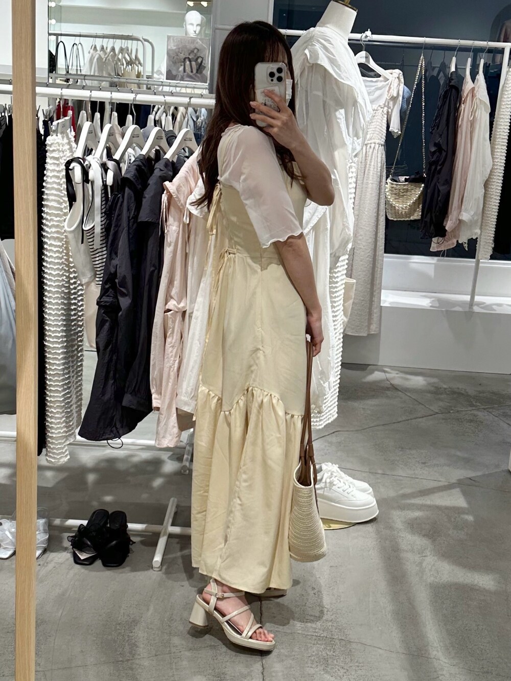 ブラウン系のトートバッグ、イエロー系のワンピース、ゴールド系のシューズを着用したレディースの春コーディネートの4枚目の写真