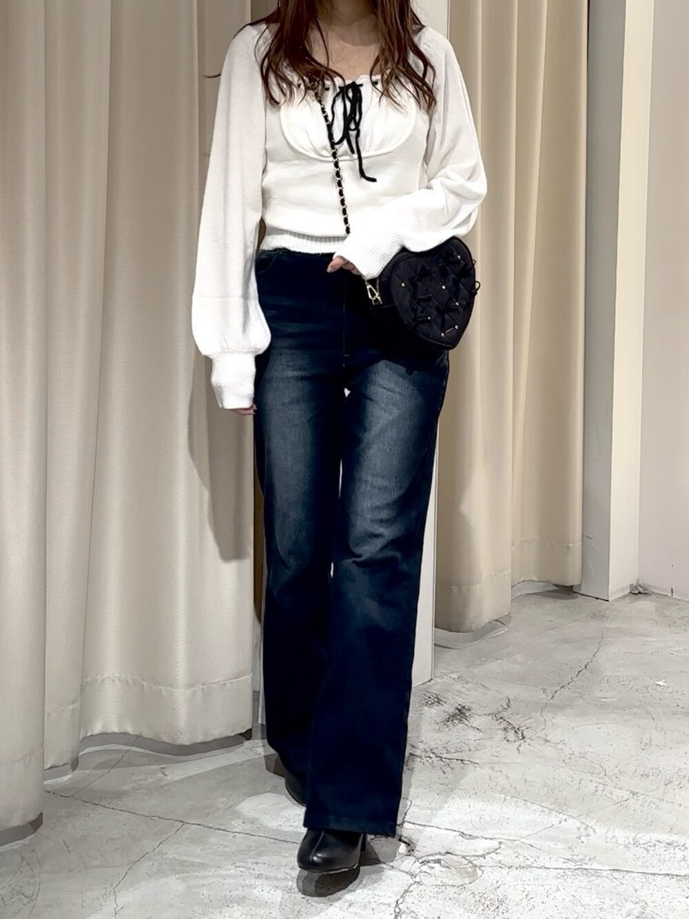 ブルー系のデニムパンツ、ホワイト系のニット/セーター、ブラック系のショルダーバッグを着用したレディースの冬コーディネートの4枚目の写真