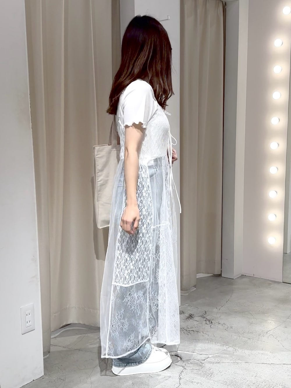 ホワイト系のワンピース、ブルー系のデニムパンツ、ホワイト系のトートバッグを着用したレディースの夏コーディネートの6枚目の写真