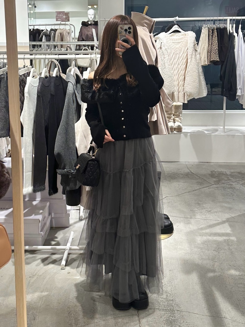 ブラック系のブーツ、グレー系のスカート、ブラック系のニット/セーターを着用したレディースの冬コーディネートの2枚目の写真