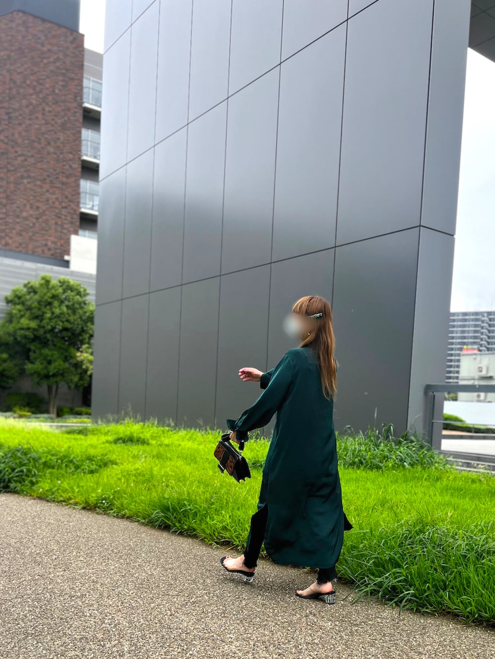 グリーン系のシャツワンピース、ブラック系のサンダル、ブラック系のデニムパンツを着用したレディースの秋コーディネートの2枚目の写真