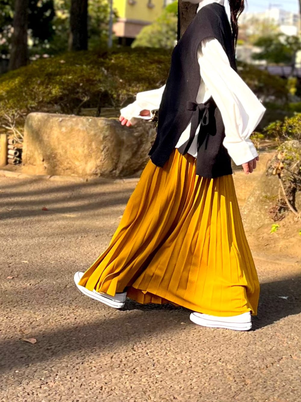 ホワイト系のシャツ/ブラウス、ブラック系のベスト、イエロー系のスカートを着用したレディースの春コーディネートの2枚目の写真