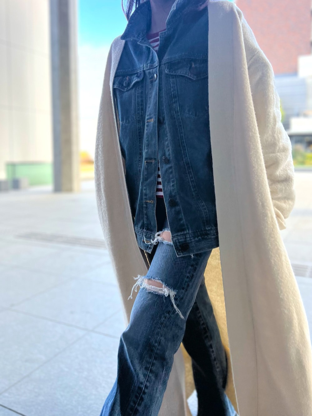 ホワイト系のカーディガン/ボレロ、ブルー系のデニムパンツ、ブラック系のブーツを着用したレディースの冬コーディネートの2枚目の写真