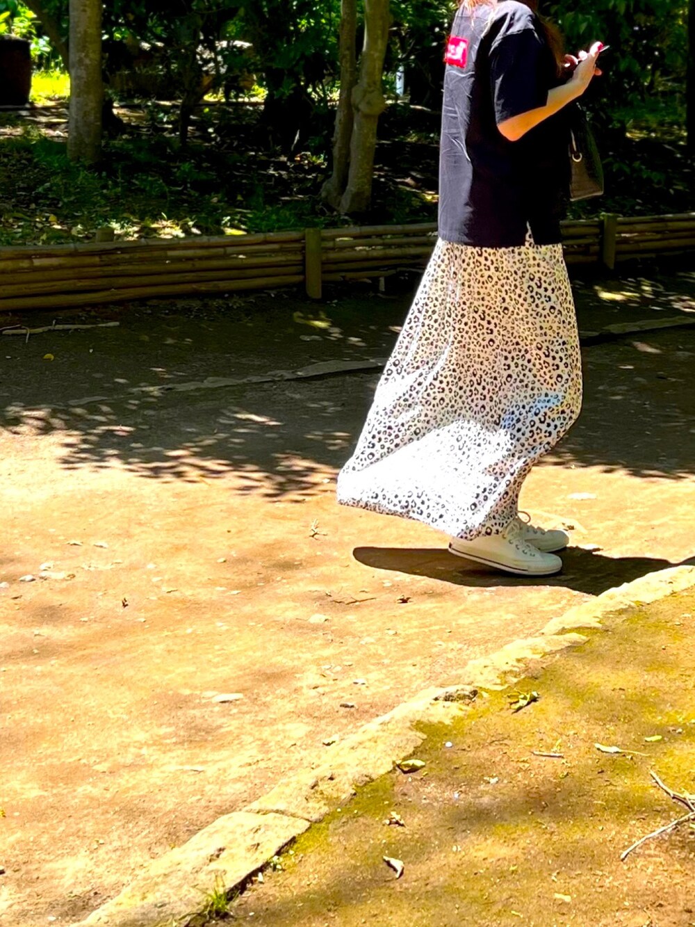 ブラック系のシャツ/ブラウス、ホワイト系のスカート、ブラック系のボストンバッグを着用したレディースの春コーディネートの2枚目の写真