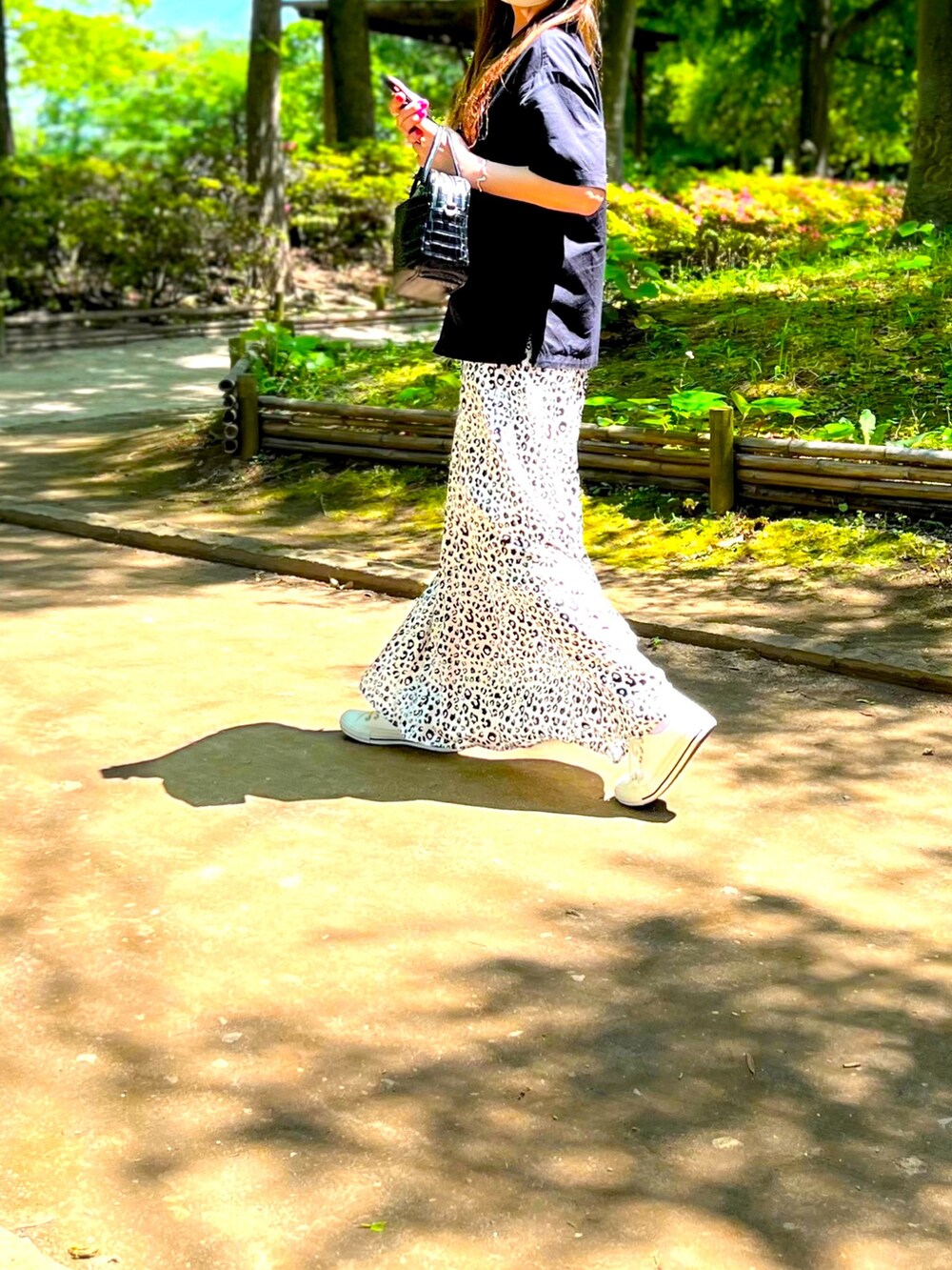 ブラック系のシャツ/ブラウス、ホワイト系のスカート、ブラック系のボストンバッグを着用したレディースの春コーディネートの4枚目の写真