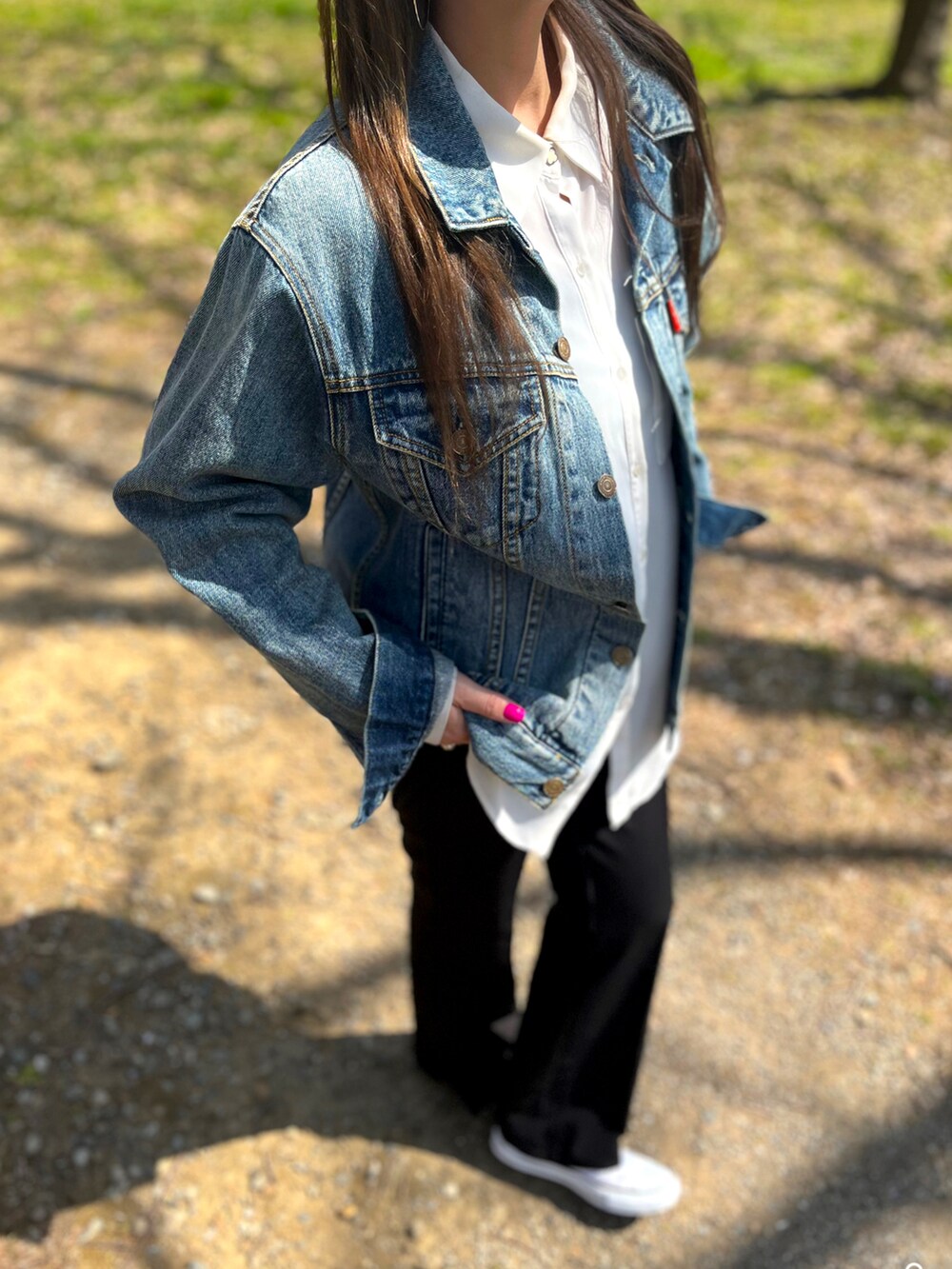 ブルー系のデニムジャケット、ブラック系のその他パンツ、ホワイト系のスニーカーを着用したレディースの春コーディネートの2枚目の写真