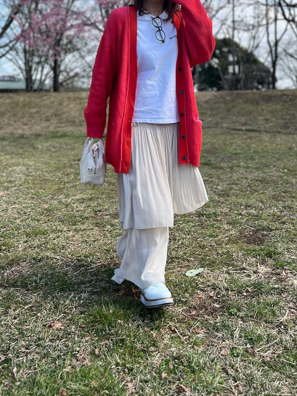 オレンジ系のカーディガン/ボレロ、ホワイト系のスカート、ホワイト系のローファーを着用したレディースの春コーディネートの5枚目の写真