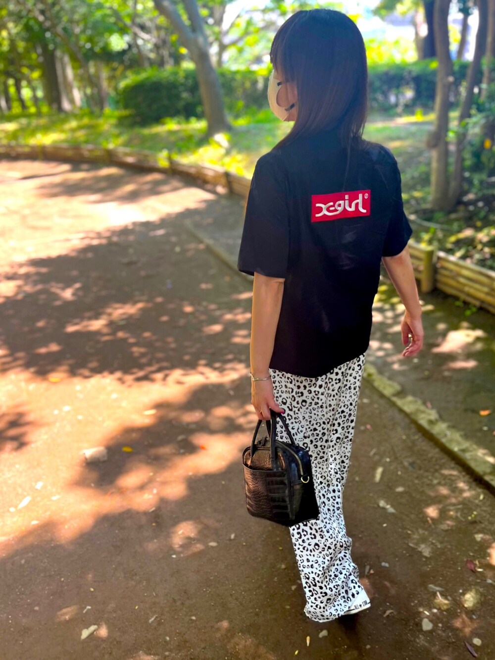 ブラック系のシャツ/ブラウス、ホワイト系のスカート、ブラック系のボストンバッグを着用したレディースの春コーディネートの3枚目の写真