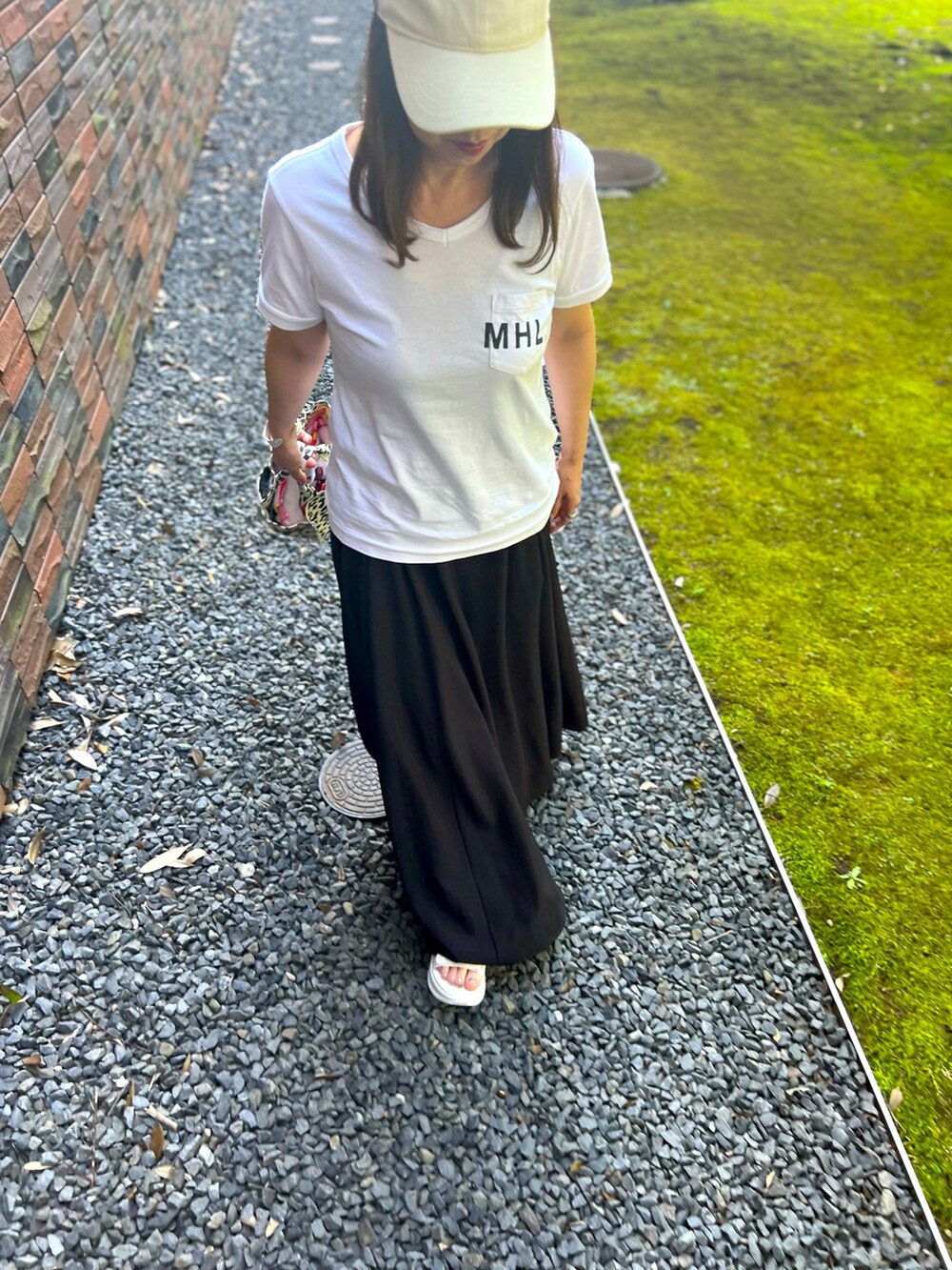 ホワイト系のサンダル、ブラック系のスカート、ホワイト系のTシャツ/カットソーを着用したレディースの夏コーディネートの5枚目の写真
