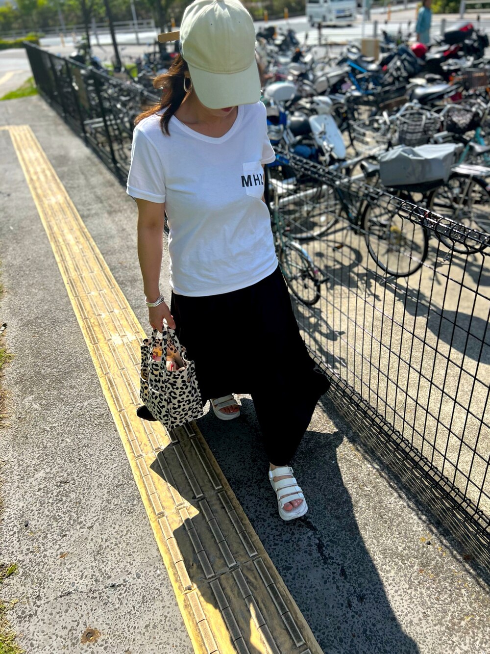 ホワイト系のサンダル、ブラック系のスカート、ホワイト系のTシャツ/カットソーを着用したレディースの夏コーディネートの3枚目の写真