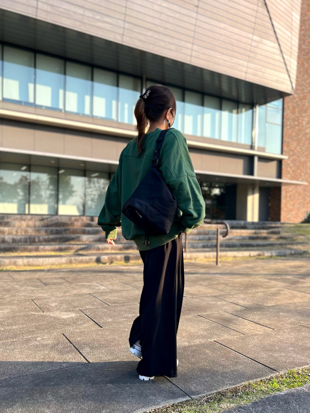 グリーン系のスウェット、ブラック系のその他パンツ、ホワイト系のスニーカーを着用したレディースの秋コーディネートの2枚目の写真