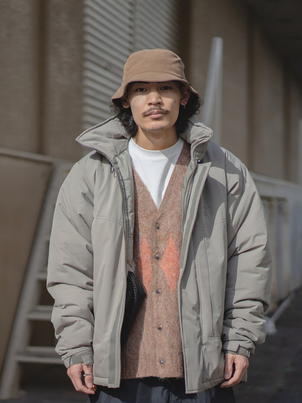 ブラウン系のカーディガン/ボレロ、ホワイト系のTシャツ/カットソー、グリーン系のダウンジャケット/コートを着用したメンズの秋コーディネートの2枚目の写真