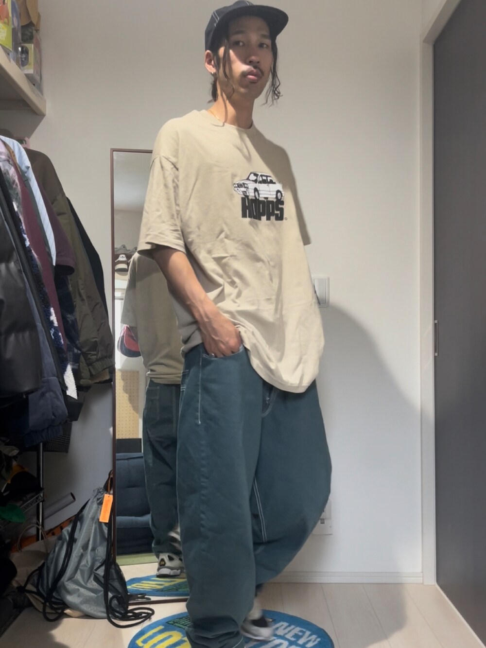 ベージュ系のトップス、グリーン系のデニムパンツ、グレー系のシューズを着用したメンズの夏コーディネートの2枚目の写真