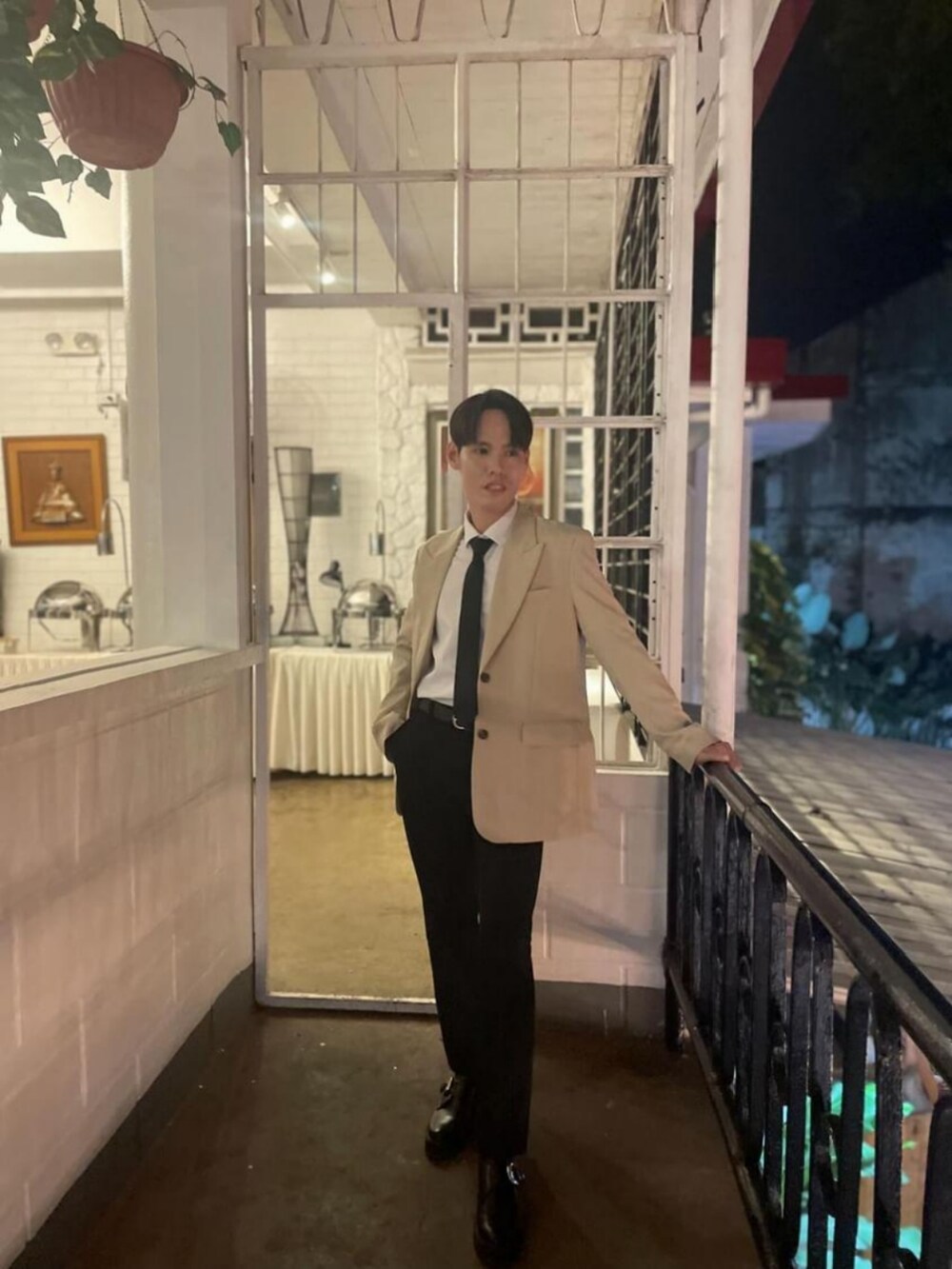 ブラック系のパンツ、ブラック系のシューズ、ホワイト系のトップスを着用したメンズの春コーディネートの3枚目の写真