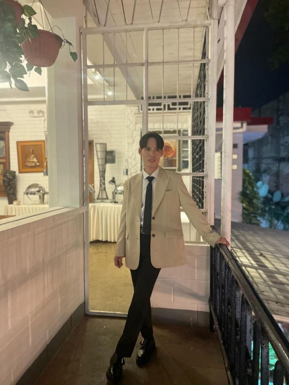 ブラック系のパンツ、ブラック系のシューズ、ホワイト系のトップスを着用したメンズの春コーディネートの2枚目の写真