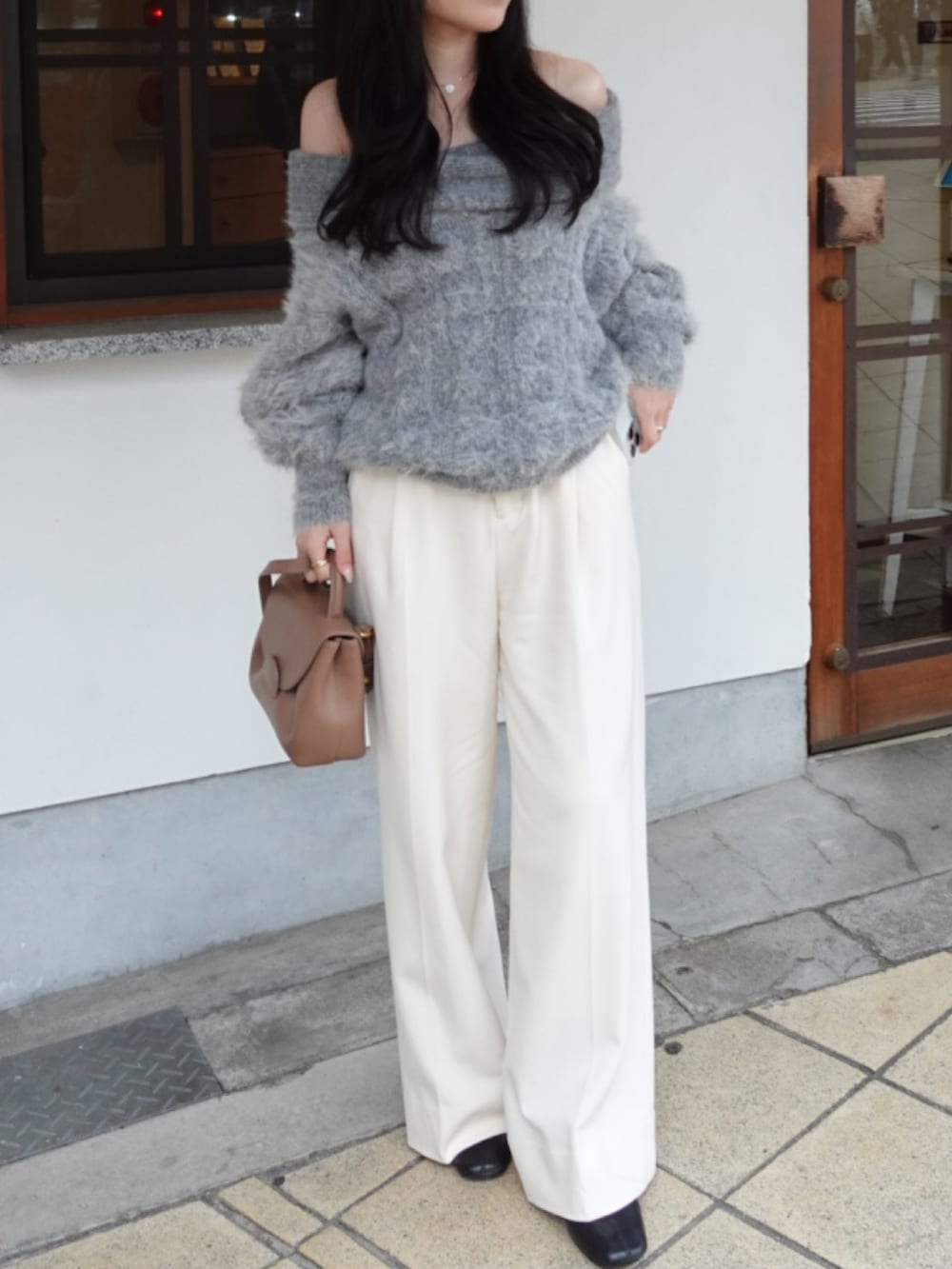 グレー系のニット/セーター、ブラウン系のハンドバッグ、ホワイト系のスラックスを着用したレディースの冬コーディネートの2枚目の写真