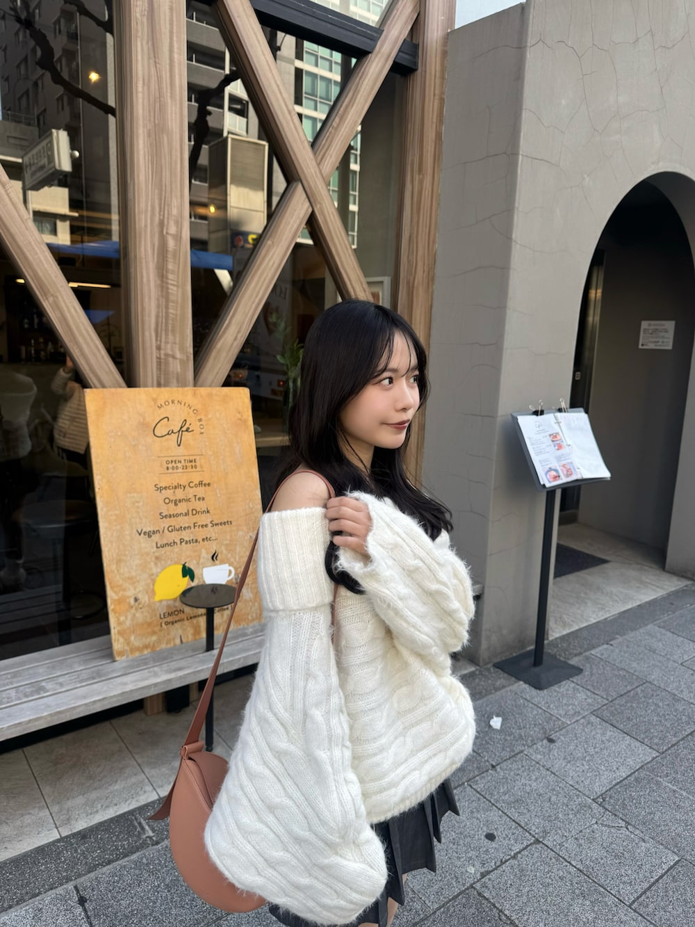 ブラウン系のブーツ、ホワイト系のニット/セーター、オレンジ系のショルダーバッグを着用したレディースの春コーディネートの2枚目の写真