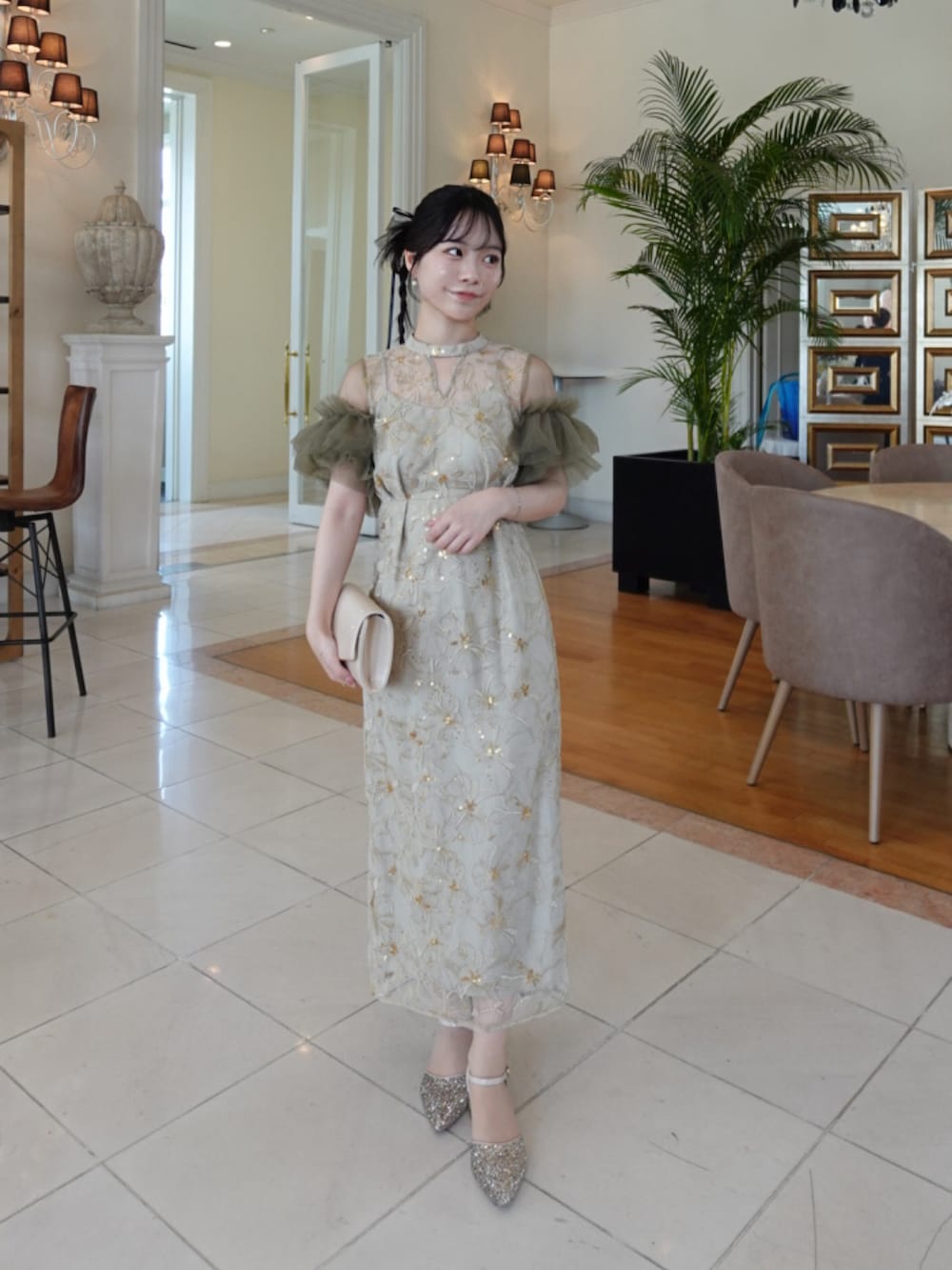 グリーン系のドレス、ベージュ系のクラッチバッグ、ゴールド系のパンプスを着用したレディースの春コーディネートの3枚目の写真