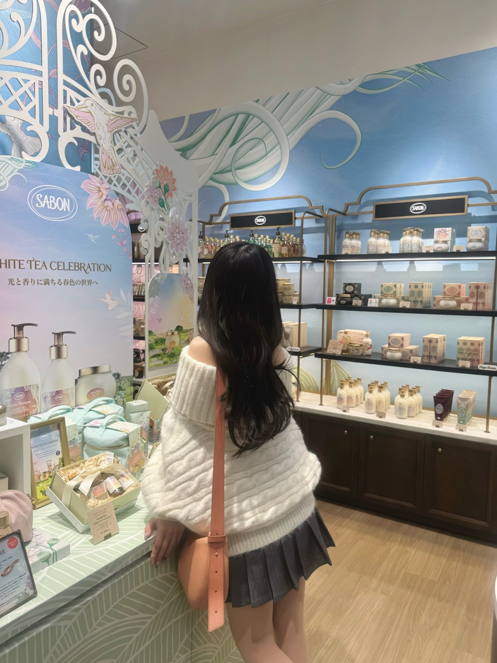 ブラウン系のブーツ、ホワイト系のニット/セーター、オレンジ系のショルダーバッグを着用したレディースの春コーディネートの3枚目の写真