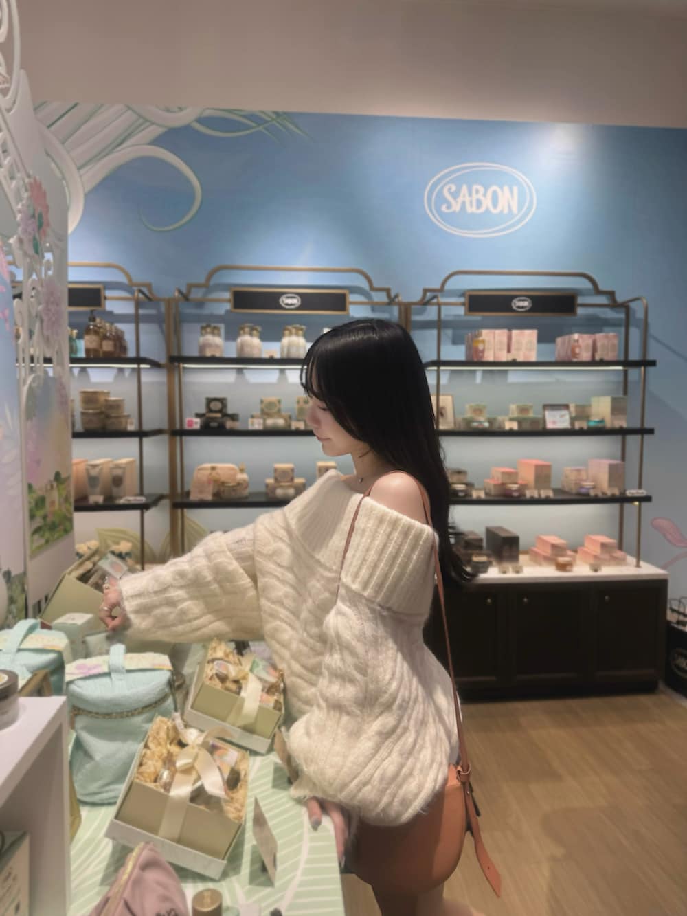 ブラウン系のブーツ、ホワイト系のニット/セーター、オレンジ系のショルダーバッグを着用したレディースの春コーディネートの4枚目の写真