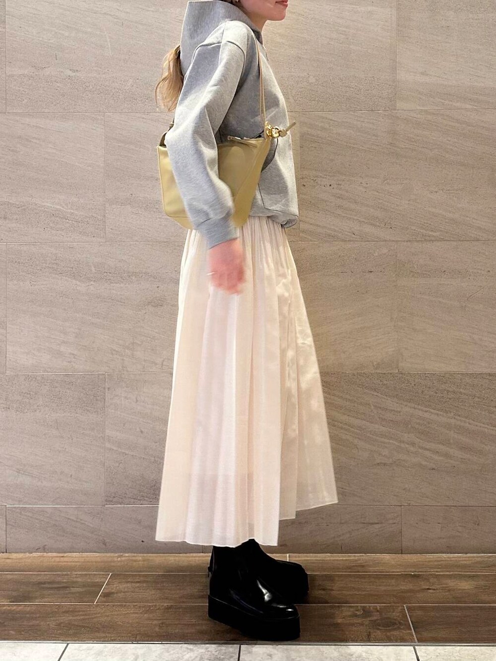 グレー系のブルゾン、ホワイト系のスカート、ベージュ系のショルダーバッグを着用したレディースの冬コーディネートの4枚目の写真