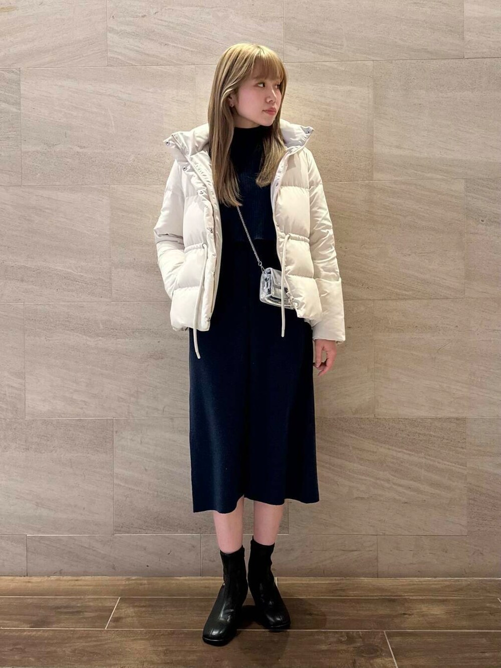 ブラック系のブーツ、ホワイト系のダウンジャケット/コート、ブルー系のワンピースを着用したレディースの冬コーディネートの3枚目の写真