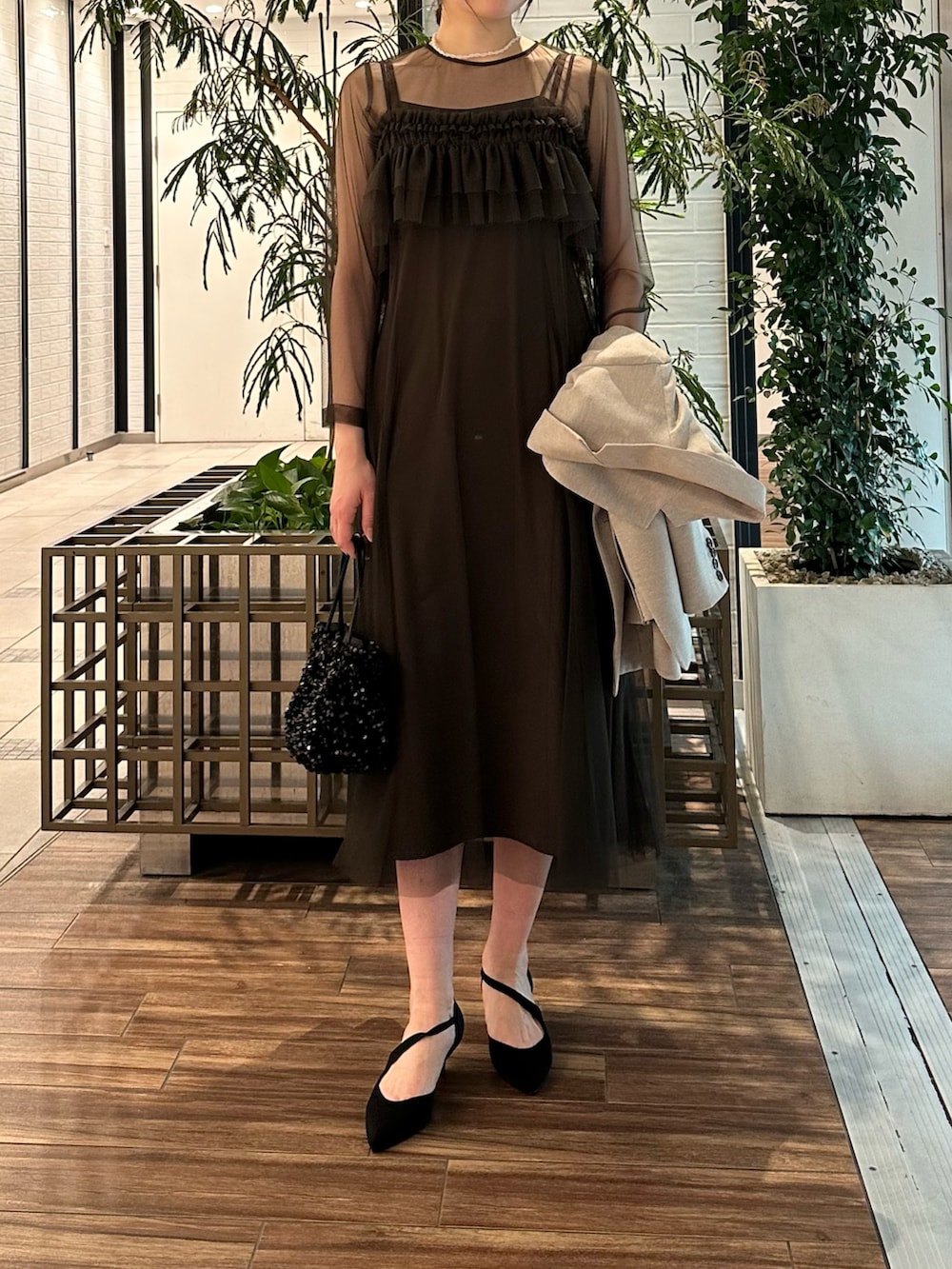 ベージュ系のその他アウター、ブラウン系のワンピース、ブラック系のハンドバッグを着用したレディースの春コーディネートの3枚目の写真