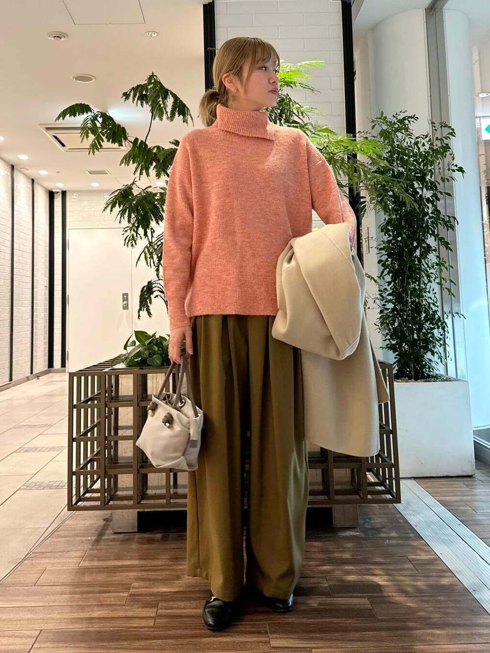 ベージュ系のステンカラーコート、ベージュ系のその他パンツ、ピンク系のニット/セーターを着用したレディースの冬コーディネートの4枚目の写真