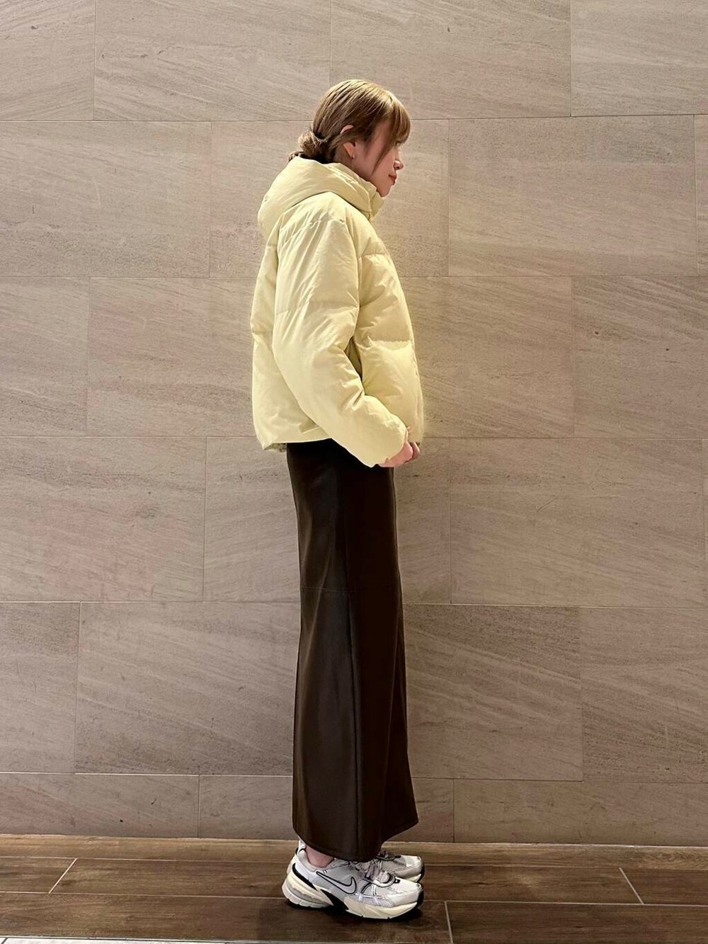 ブラウン系のスカート、イエロー系のダウンジャケット/コート、ホワイト系のスニーカーを着用したレディースの冬コーディネートの4枚目の写真