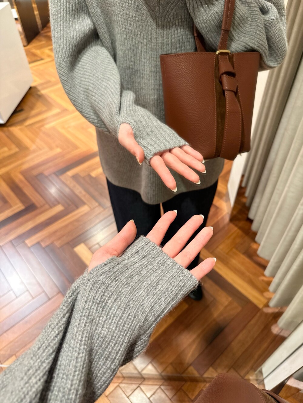 グレー系のニット/セーター、ホワイト系のTシャツ/カットソー、ブルー系のデニムパンツを着用したレディースの秋コーディネートの6枚目の写真