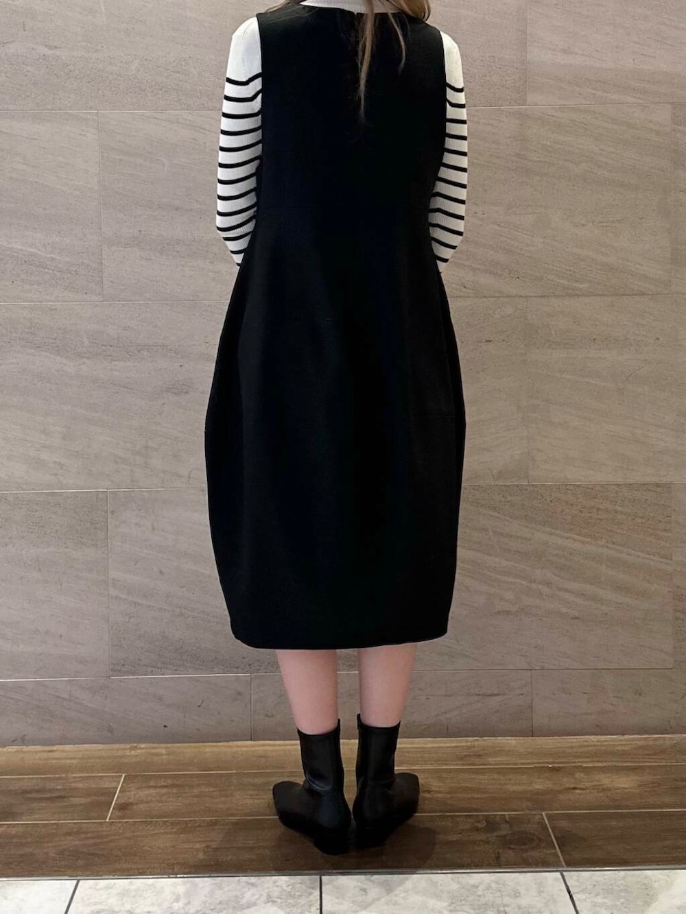 ホワイト系のニット/セーター、ブラック系のジャンパースカート、ブラック系のブーツを着用したレディースの冬コーディネートの5枚目の写真