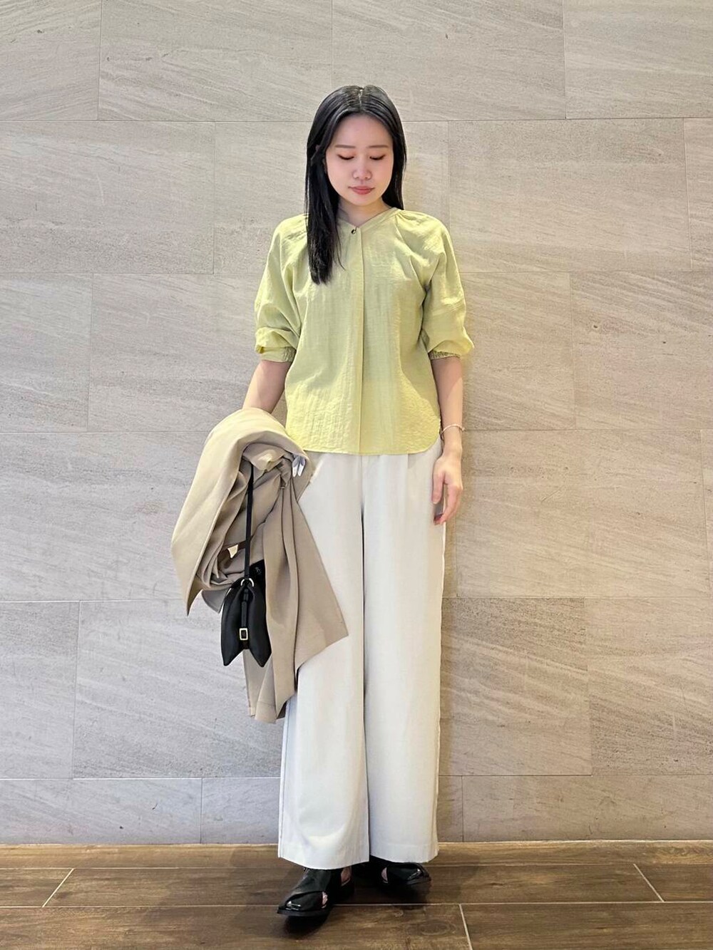 イエロー系のシャツ/ブラウス、ベージュ系のトレンチコート、ベージュ系のその他パンツを着用したレディースの春コーディネートの6枚目の写真
