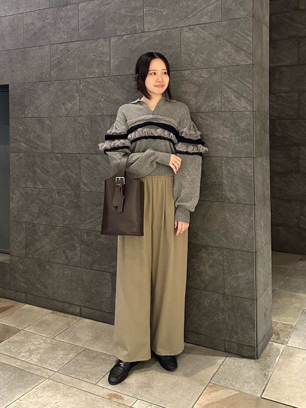 ブラウン系のショルダーバッグ、ベージュ系のその他パンツ、グレー系のニット/セーターを着用したレディースの秋コーディネートの2枚目の写真