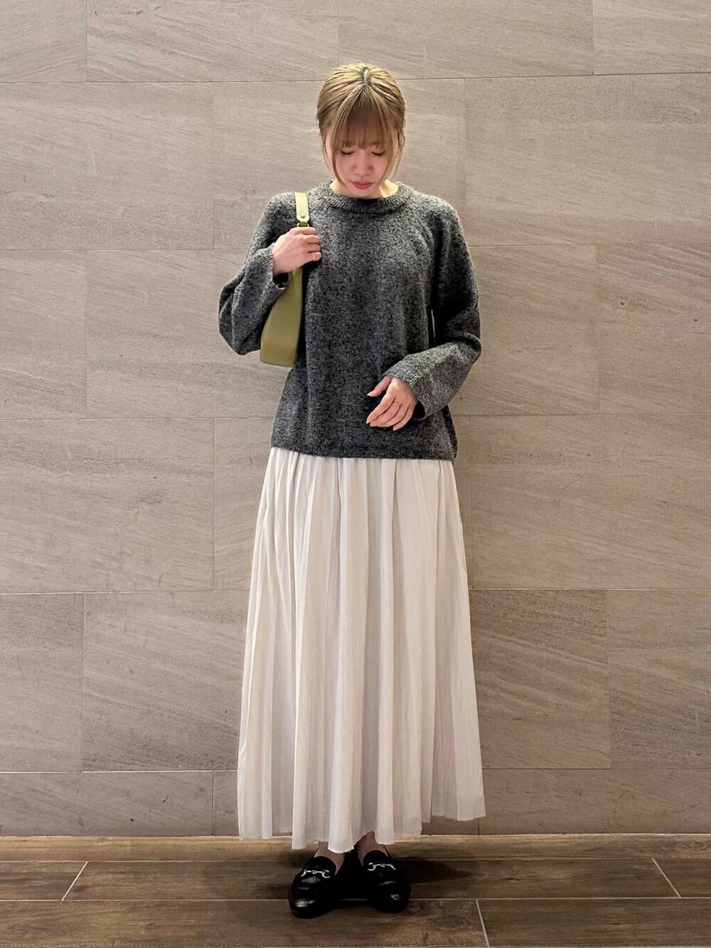 グリーン系のショルダーバッグ、ホワイト系のスカート、グレー系のニット/セーターを着用したレディースの冬コーディネートの2枚目の写真